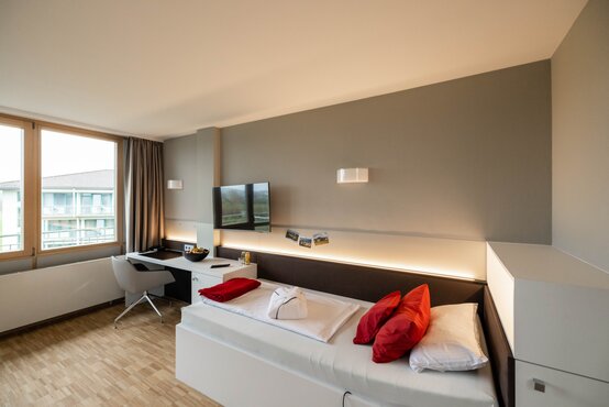 Modernes, barrierefreies Komfortzimmer in der Klinik mit großem Fenster, Balkonblick, Holzboden und stilvoller Einrichtung