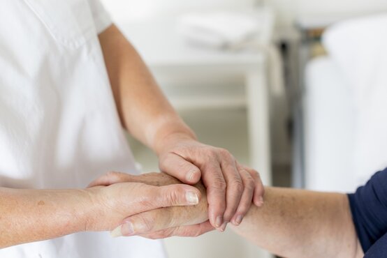 Pflegekraft hält fürsorglich die Hand einer Patientin