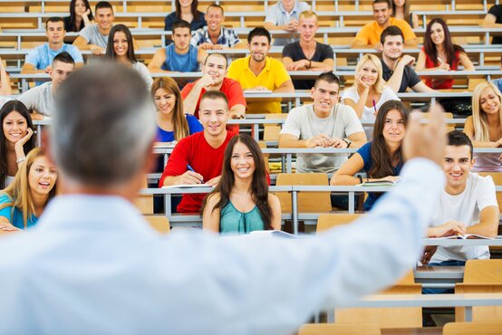 Dozent im hellen Hemd hält Vortrag im großen Hörsaal vor Studierenden