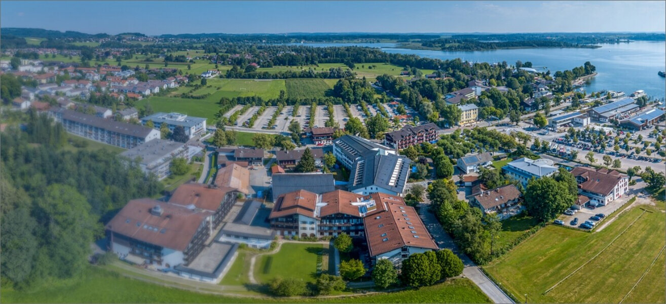 Luftaufnahme der Schön Klinik Roseneck am See, umgeben von Grünflächen, Parkplätzen und moderner Infrastruktur