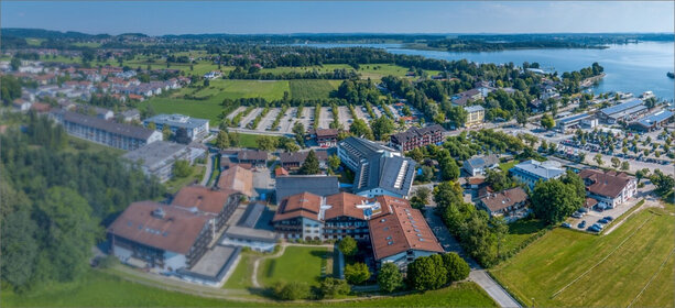 Luftaufnahme der Schön Klinik Roseneck am See, umgeben von Grünflächen, Parkplätzen und moderner Infrastruktur