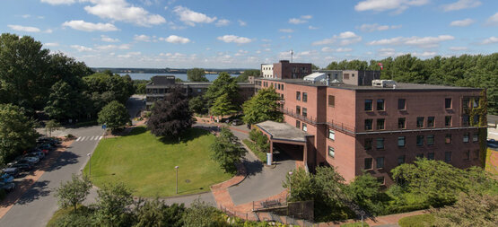 Panoramic view of the Schön Klinik Eckernförde with lawn, trees, driveway, road and lake