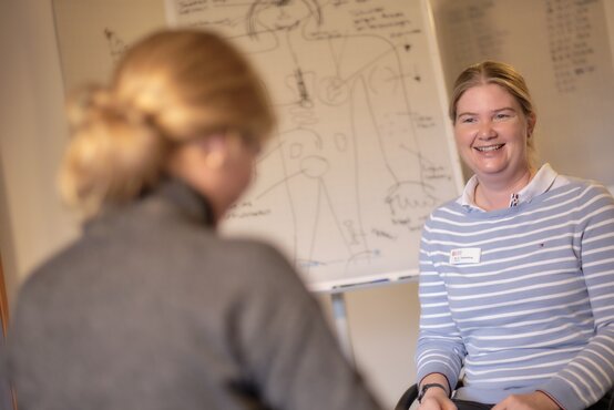 Jugendliche und Therapeutin im Gespräch vor Whiteboard mit anatomischer Zeichnung in heller Therapiepraxis