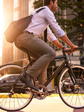 Geschäftsmann in Businesskleidung fährt morgens bei Sonnenschein mit dem Fahrrad durch die Stadt
