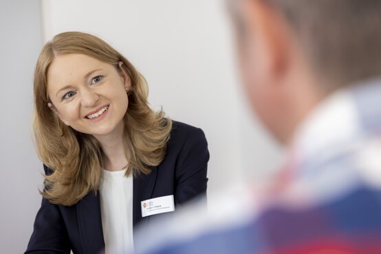 Freundliche Psychotherapeutin im Gespräch mit Patient in moderner Praxis, empathisch und aufmerksam