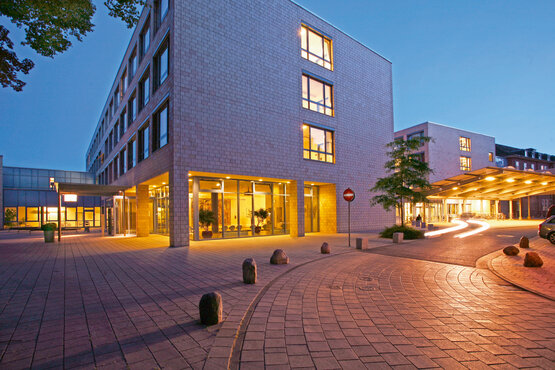 Aufnahme der Schön Klinik Hamburg Eilbek im dunklen, mit Auffahrt und beleuchtetem Eingangsbereich