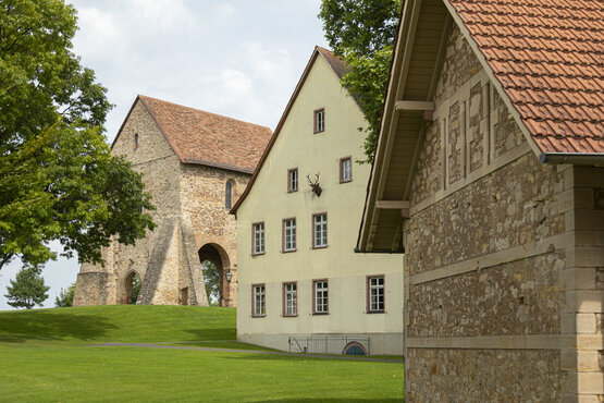 Historische Gebäude mit roten Ziegeldächern auf grüner Rasenfläche im Klosterpark Lorsch