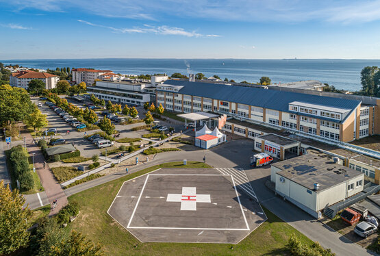 Luftaufnahme einer Klinik am Meer mit Hubschrauberlandeplatz