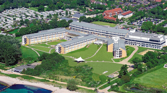 Luftaufnahme der Schön Klinik Neustadt mit grüner Umgebung und Küstenlinie