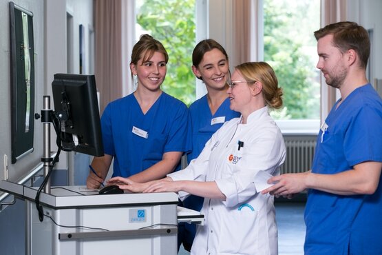 Pflegeschüler und Ausbilderin bei praktischer Anleitung am Computer in Schön Klinik, Pflegeausbildung, Teamarbeit