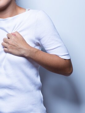 Frau hält sich die Brust wegen akuter Brustschmerzen