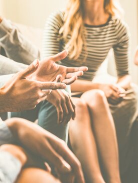 Mehrere Personen sitzen im Kreis und sprechen miteinander während einer Gruppentherapie