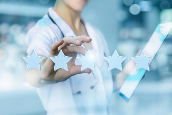 Ärztin bewertet fünf Sterne am Tablet, Symbol für Patientenzufriedenheit und Qualität