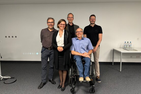 Fünf Personen, darunter ein Mann im Rollstuhl, posieren auf einem medizinischen Symposium zum Thema Schlaflabor