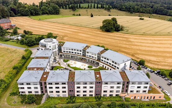 Luftaufnahme der Schön Klinik Bad Arolsen mit halbkreisförmiger Architektur, begrünten Flachdächern und großem Innenhof