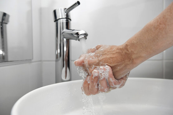 Person wäscht sich gründlich die Hände mit Seife unter fließendem Wasser