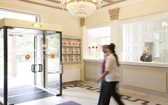 Heller Eingangsbereich mit automatischer Glastür, Empfangstheke