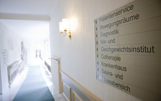Wegweiser mit Schildern zu Patientenservice, Diagnostik, Bewegungsräumen, Hör- und Gleichgewichtsinstitut, Cotherapie, Krankenhaus, Sauna- und Fitnessbereich
