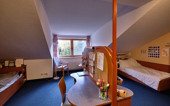 Zweibettzimmer mit zwei Einzelbetten, Schreibtisch, persönlicher Dekoration und großem Fenster im Dachgeschoss