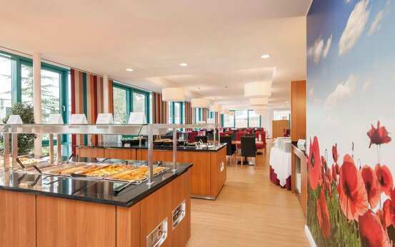 Modernes, helles Selbstbedienungsrestaurant mit großen Fenstern, Essensstationen und Mohnblumenwand