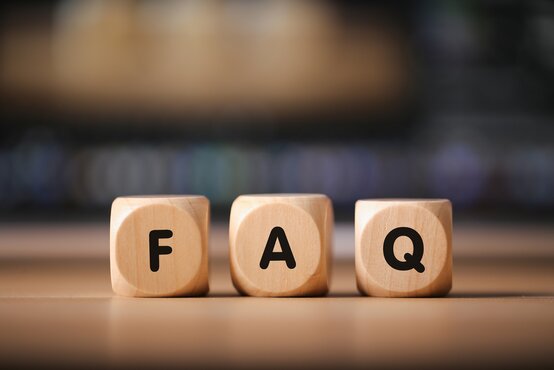 Drei Holzklötze mit den Buchstaben F, A und Q als Symbol für FAQ, Kundenservice und Hilfeseite auf Tisch