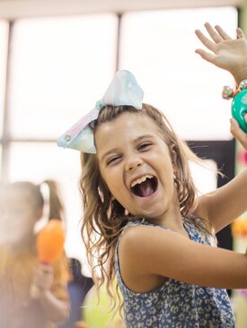 Kleines Mädchen lacht und hat eine Rassel in der Hand