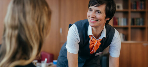 Freundliche Mitarbeiterin am Empfangstresen einer medizinischen Einrichtung, bereit für Patientenanfragen