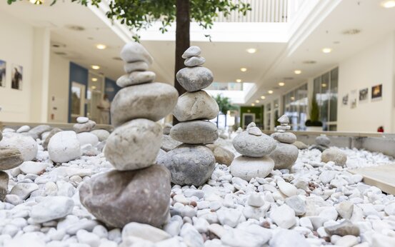 Heller Innenhof einer modernen Klinik mit Natursteinen, begrünten Elementen und großen Fenstern für viel Tageslicht