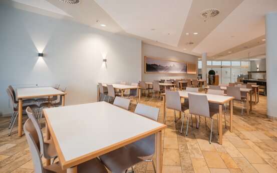 Heller, moderner Speisesaal mit leeren Holztischen und Stühlen und Selbstbedienungsbereich