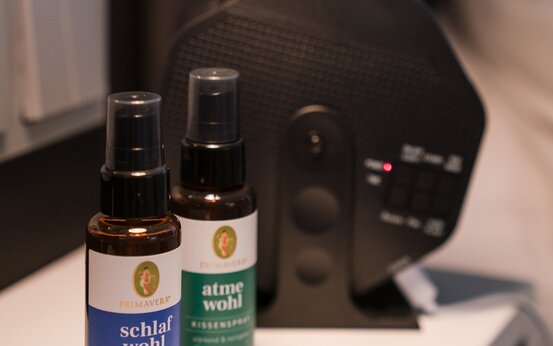 Zwei Kissensprays „schlaf wohl“ und „atme wohl“ auf weißem Nachttisch im Klinikzimmer