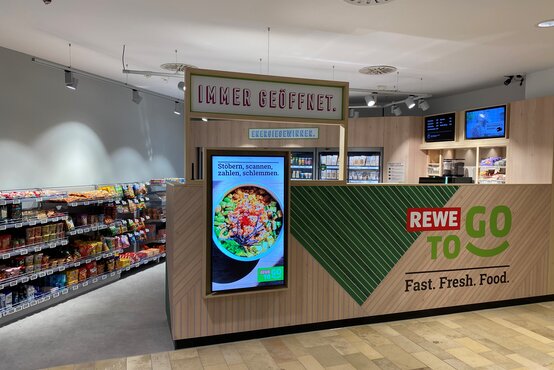 Moderne REWE To Go-Filiale mit Selbstbedienung, Snack- und Getränkebereich, gut sichtbarem REWE To Go-Logo