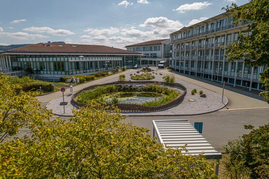 Schön Klinik Bad Staffelstein mit Glasfassade, Flachbau, Innenhof mit Teich, Rundweg, Bäumen und Parkplätzen