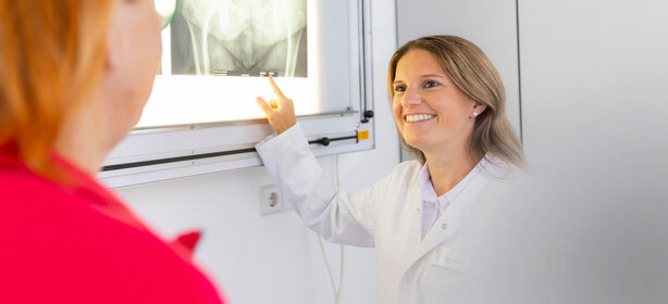 Ärztin erklärt Patientin freundlich eine Becken-Röntgenaufnahme in moderner Praxis