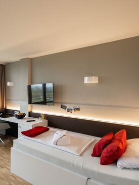 Modernes, barrierefreies Komfortzimmer in der Klinik mit großem Fenster, Balkonblick, Holzboden und stilvoller Einrichtung