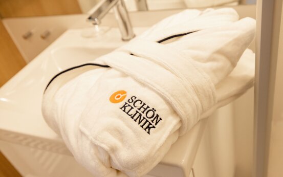 Hochwertiger Bademantel mit Schön Klinik Logo auf modernem Waschbecken