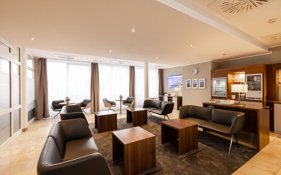 Modernes Komfortzimmer mit schwarzen Ledersesseln, Sofas, Holztischen, großem Fenster und Snackbereich