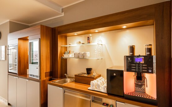 Moderne Kaffeestation mit großer Kaffeemaschine, Spüle, Glasregalen und Getränkekühlschrank