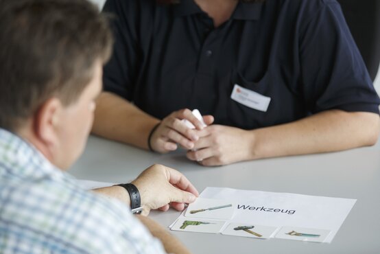 Therapeutische Sitzung in der Logopädie: Patient zeigt auf Werkzeug-Bilderkarten