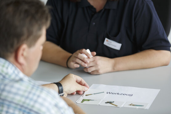 Therapeutische Sitzung in der Logopädie: Patient zeigt auf Werkzeug-Bilderkarten
