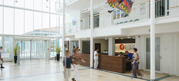 Heller, moderner Empfangsbereich der Schön Klinik mit Glasfront, Pflanzen und Empfangstresen