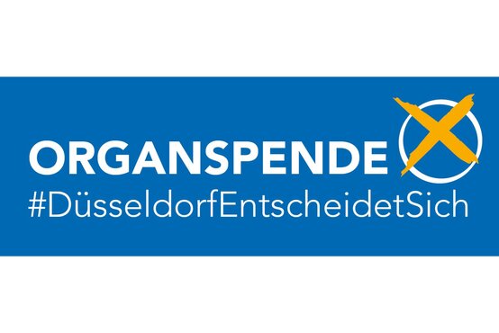 Blaues Banner mit weißer Aufschrift „ORGSPENDE“, Hashtag „#DüsseldorfEntscheidetSich“ und gelbem Kreuz im weißen Kreis