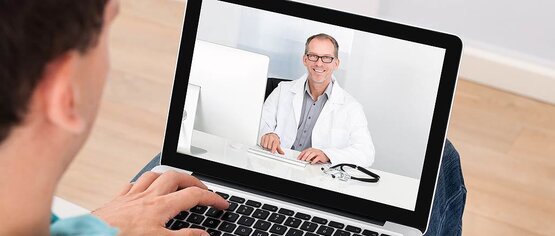 Patient hält Laptop mit Videokonferenz zu Hause, Arzt im weißen Kittel berät online