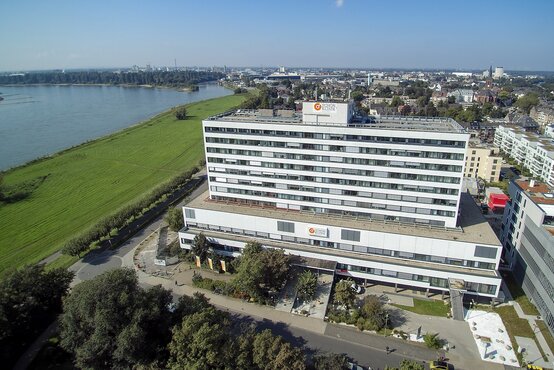 Luftaufnahme der modernen Schön Klinik Düsseldorf am Rhein mit Grünflächen und Stadtpanorama im Hintergrund