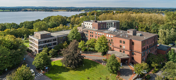 Luftaufnahme der Schön Klinik Eckernförde mit Hauptgebäude und Blick auf den Windebyer Noor
