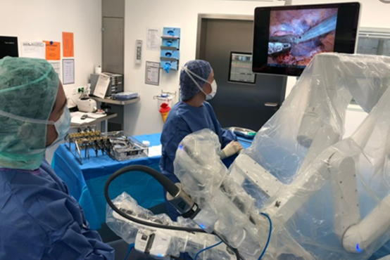 Zwei Chirurgen in OP-Kleidung bedienen ein Operationsrobotersystem im modernen Klinik-OP