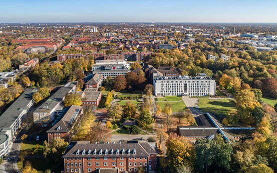 Luftaufnahme der Schön Klinik Hamburg Eilbek mit heller Fassade, umgeben von herbstlichen Bäumen und Stadtgebiet bei Sonnenschein