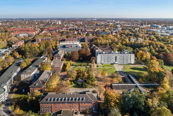 Luftaufnahme der Schön Klinik Hamburg Eilbek mit heller Fassade, umgeben von herbstlichen Bäumen und Stadtgebiet bei Sonnenschein