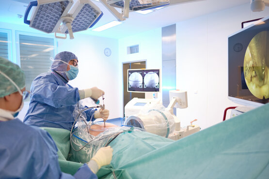 Steril bekleidete Ärzte führen endoskopische Bandscheibenoperation mit OP-Instrumenten
