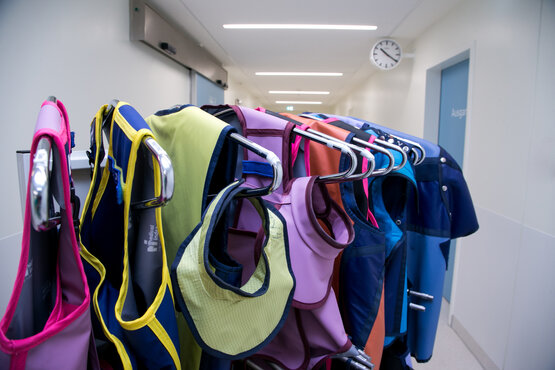 Mehrere bunte Röntgenschutzschürzen hängen auf Kleiderbügeln