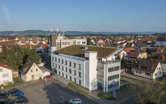 Luftaufnahme der Schön Klinik Lorsch mit begrüntem Flachdach, Parkplatz, umliegenden Wohnhäusern und grünen Hügeln im Hintergrund